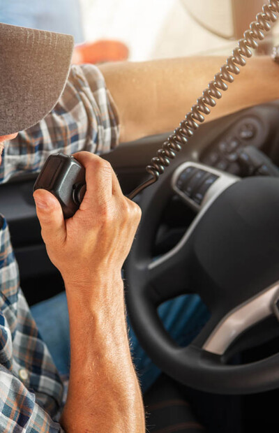 Caucasian Trucker in His 40s Making Conversation Using CB Radio Inside His Semi Truck Cabin. Convoy Truck Drivers Communication Theme.