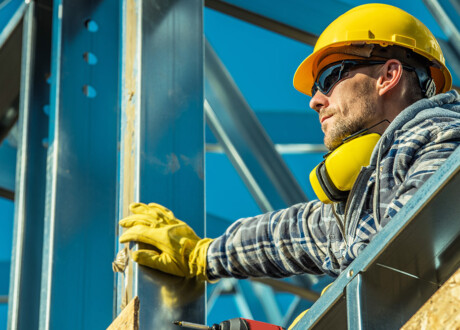 Construction Worker Portrait. Caucasian Builder in Yellow Hard Hat and Noise Reduction Headphones. Industrial Theme.