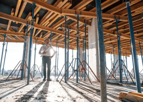 Beautiful sunlight. Walking with plan in hands. Man is working on the construction site at daytime.